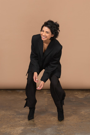 Front view of a squatting businesswoman smiling and looking at camera