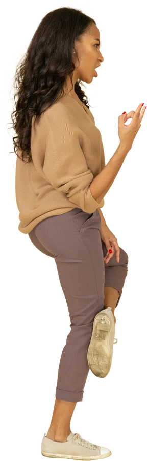 Side view of a screaming dark-skinned young female showing rock gesture
