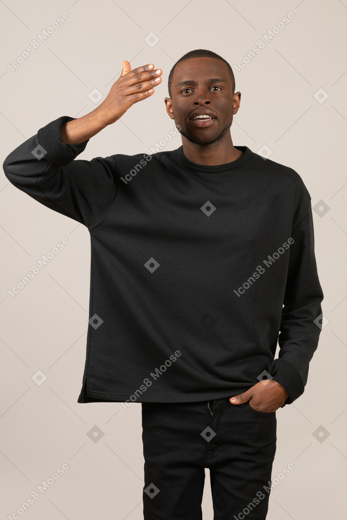 Young man in black outfit holding his hand up