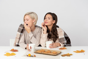 Mujeres jóvenes bebiendo café matutino y bostezando