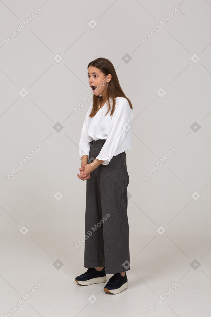 Three-quarter view of a shocked young lady in office clothing holding hands together
