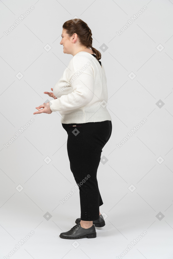 Mujer regordeta en suéter blanco de pie en el perfil