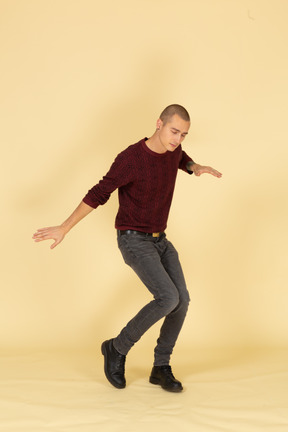 赤いプルオーバーで踊っている若い男の4分の3のビュー