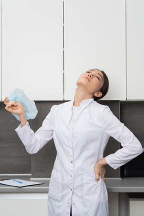 Front view of a tired female doctor throwing head back