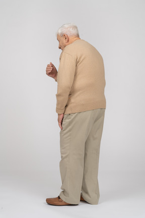 Side view of an old man in casual clothes explaining something