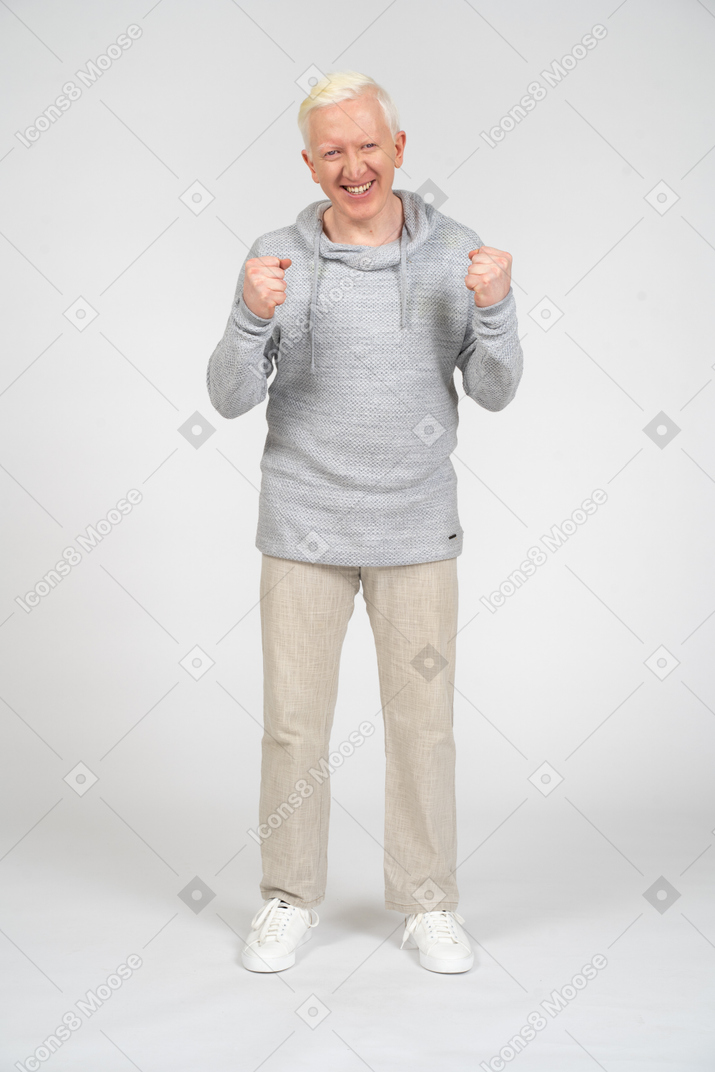 Vista frontal de um homem de pé com as duas mãos em punhos e sorrindo