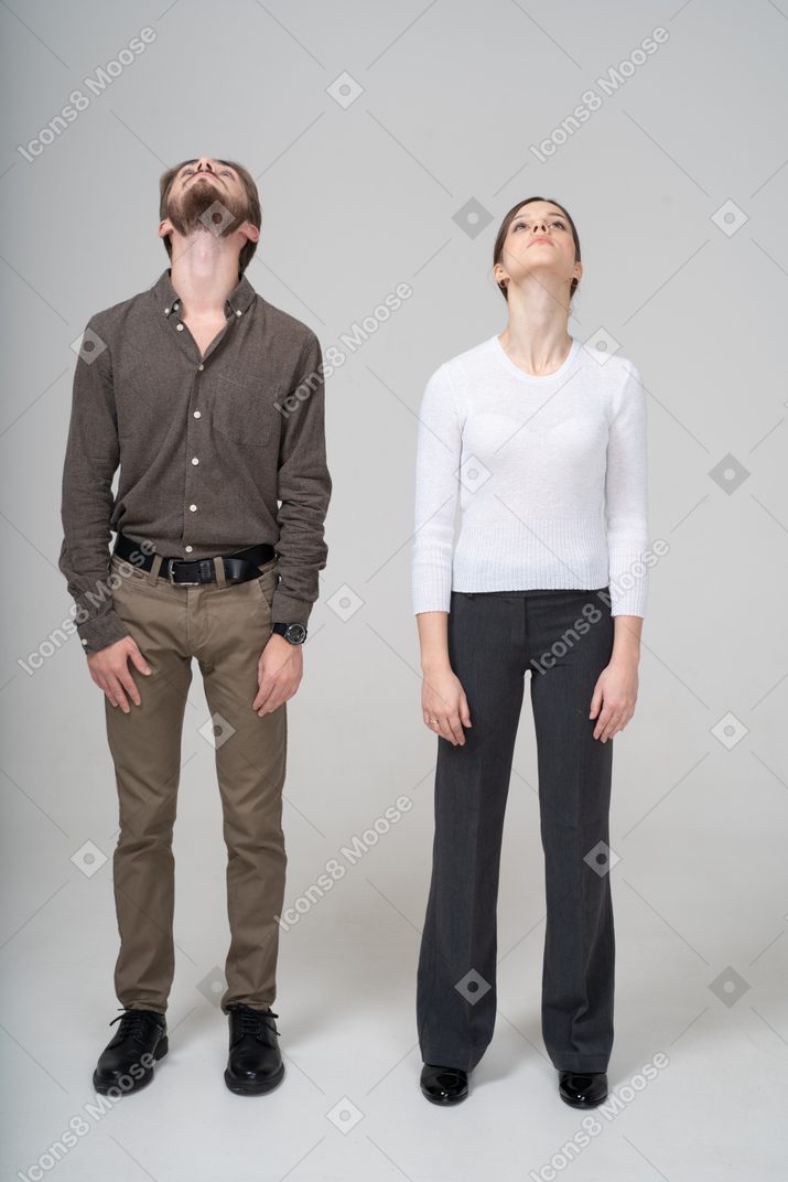 Vista frontal de um jovem casal com roupas de escritório, olhando para cima