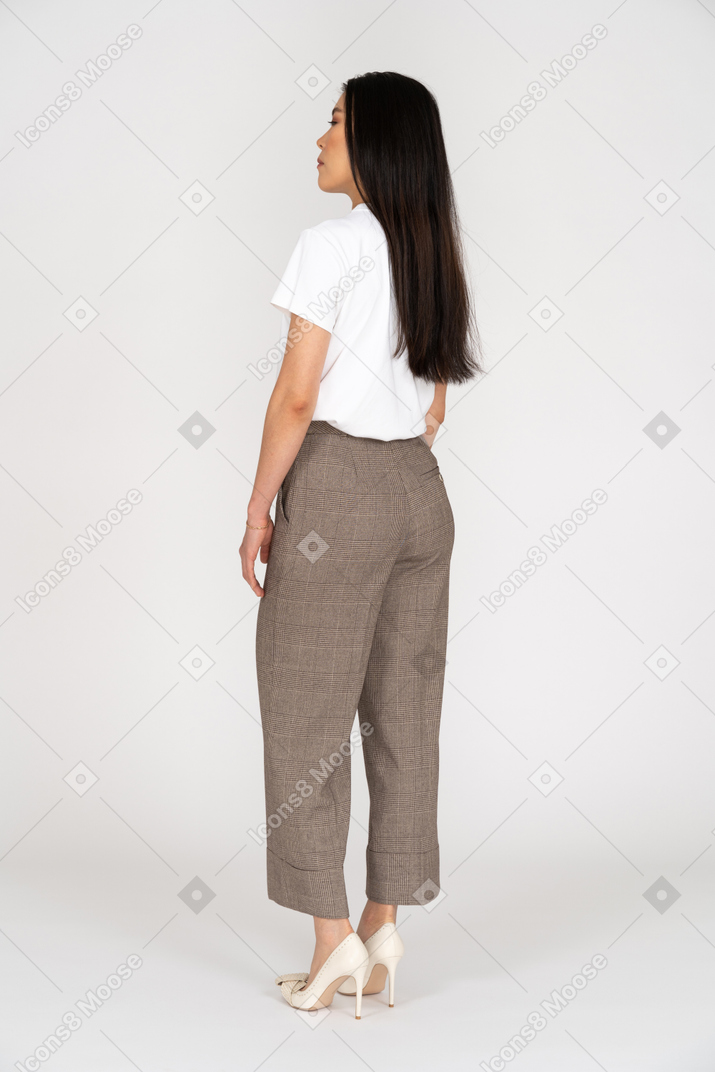 Vista posteriore di tre quarti di una giovane donna in calzoni che sta ferma con gli occhi chiusi