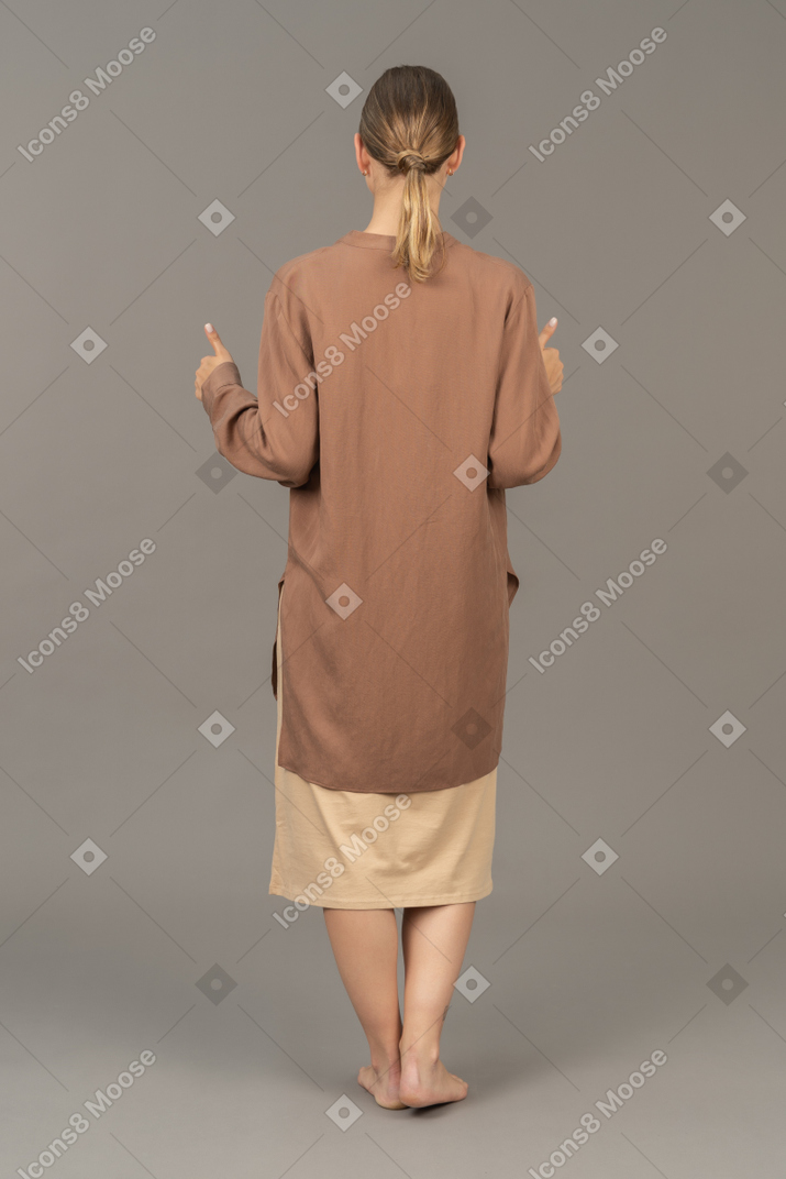 親指を立てて立っている女性の背面図