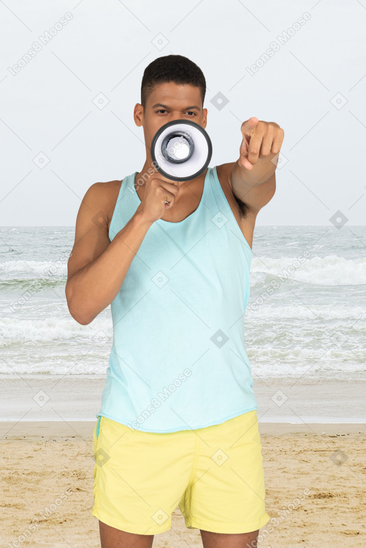 A lifeguard speaking into a megaphone on a beach