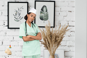 A woman in scrubs standing in front of a brick wall