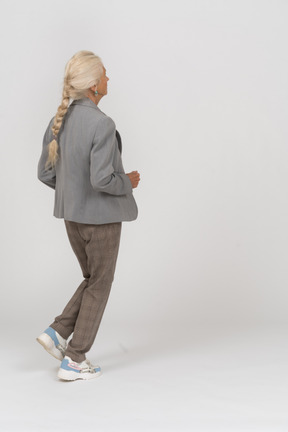 Side view of an old lady in suit running