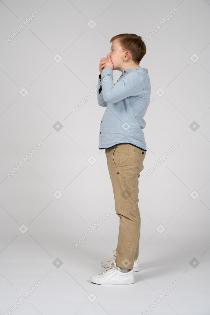 Scared boy covering mouth with hands