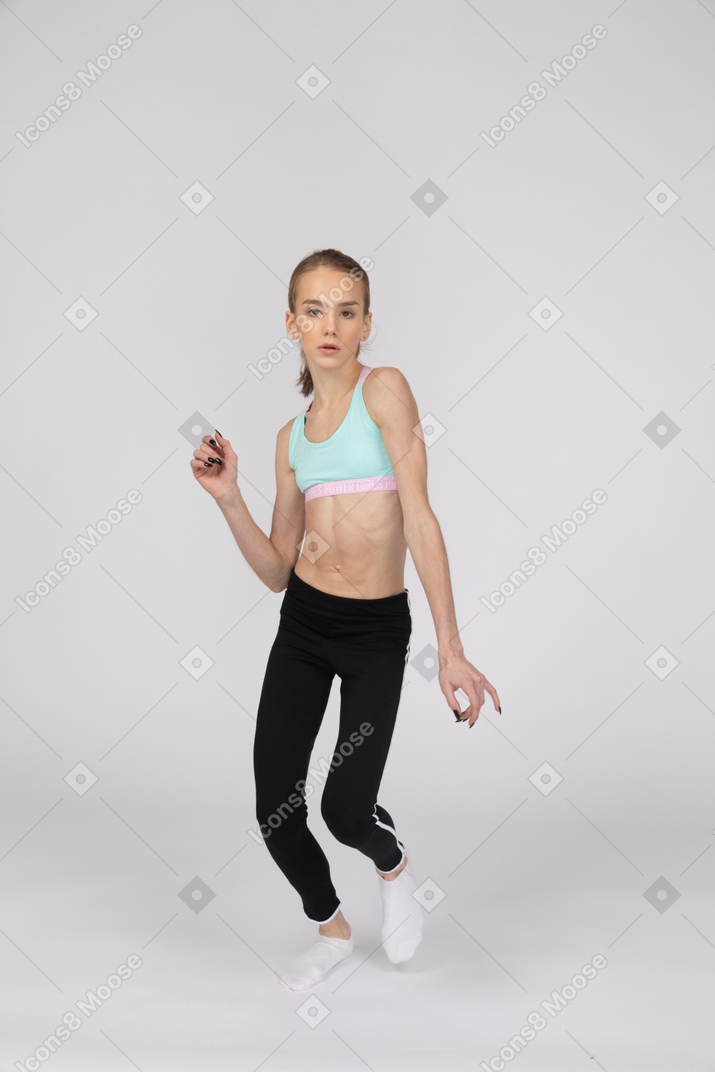 一个年轻的女孩，穿着运动衣跳舞，看着相机的前视图