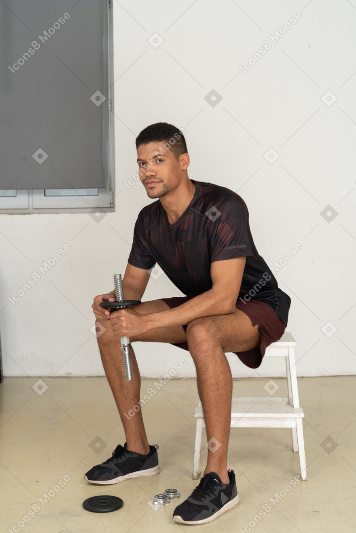 Молодой человек в спортивной одежде сидит на белом стуле