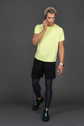 Front view of a dark-skinned young man having a phone call