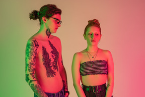 Hombre tatuado y su novia de pie en luces de neón
