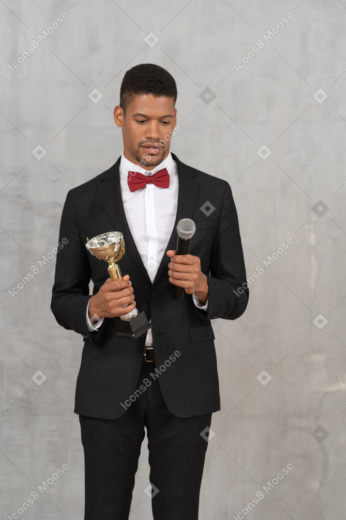 Hombre sorprendido sosteniendo un premio y un micrófono