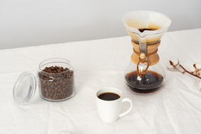 Chemex, tasse kaffee und glas mit kaffeebohnen