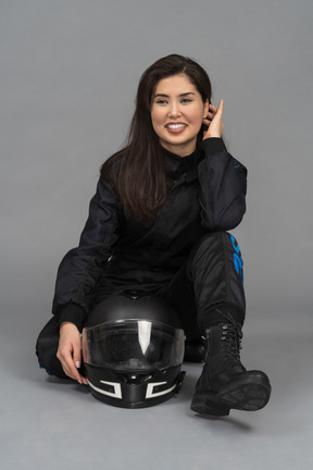 Um motociclista feminino alegre, sentado na frente de uma câmera