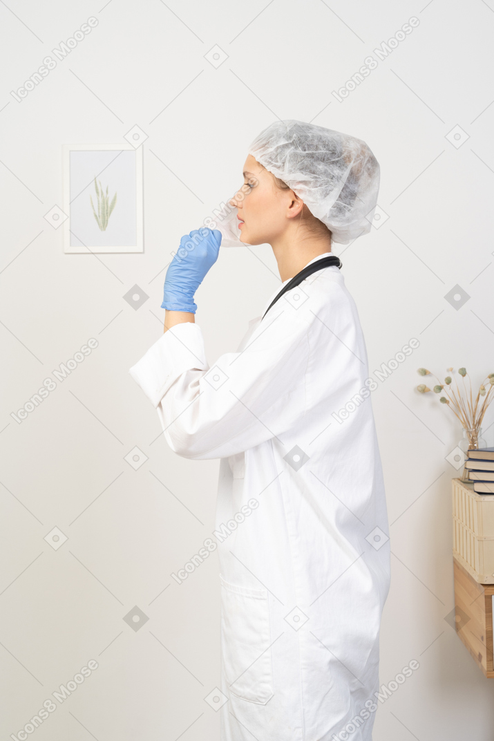 Side view of a young female doctor putting on a mask