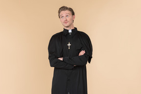Pensive catholic priest standing with hands folded