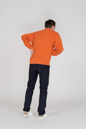 Junger mann im orangefarbenen sweatshirt stehend