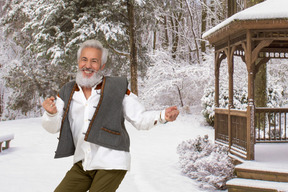 A man with a beard standing in the snow in front of a gazebo