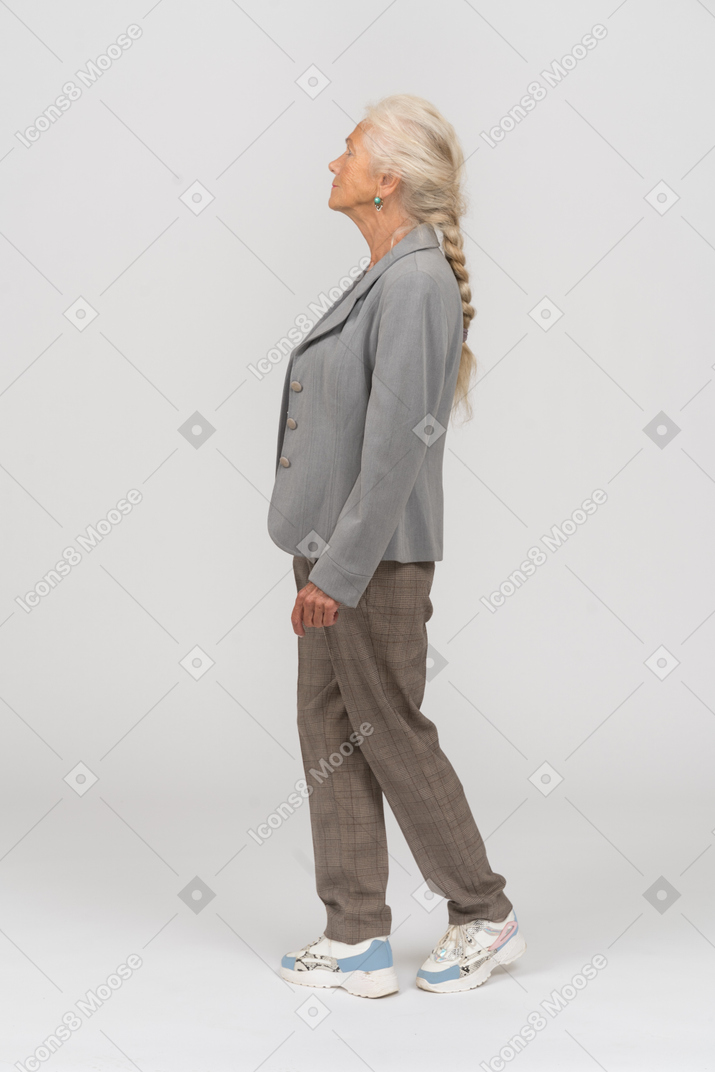 Vista laterale di una vecchia signora in abito che cammina