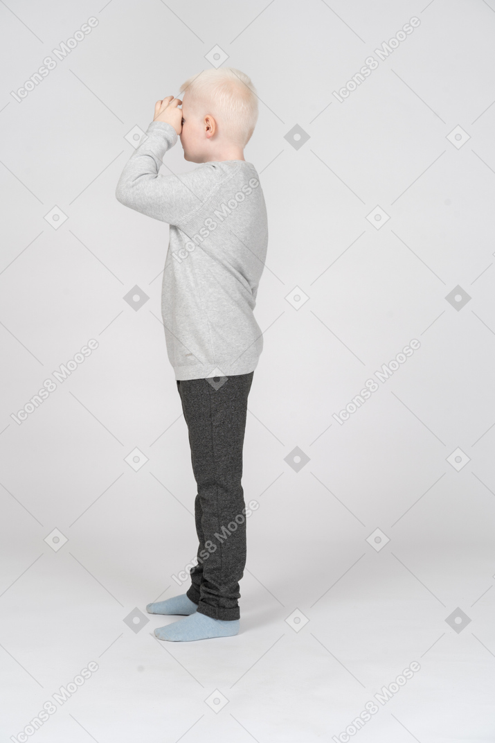 Vista lateral de um menino olhando através de binóculos imaginários