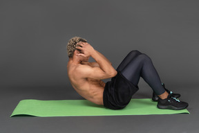 Side view of a shirtless afro man doing crunches