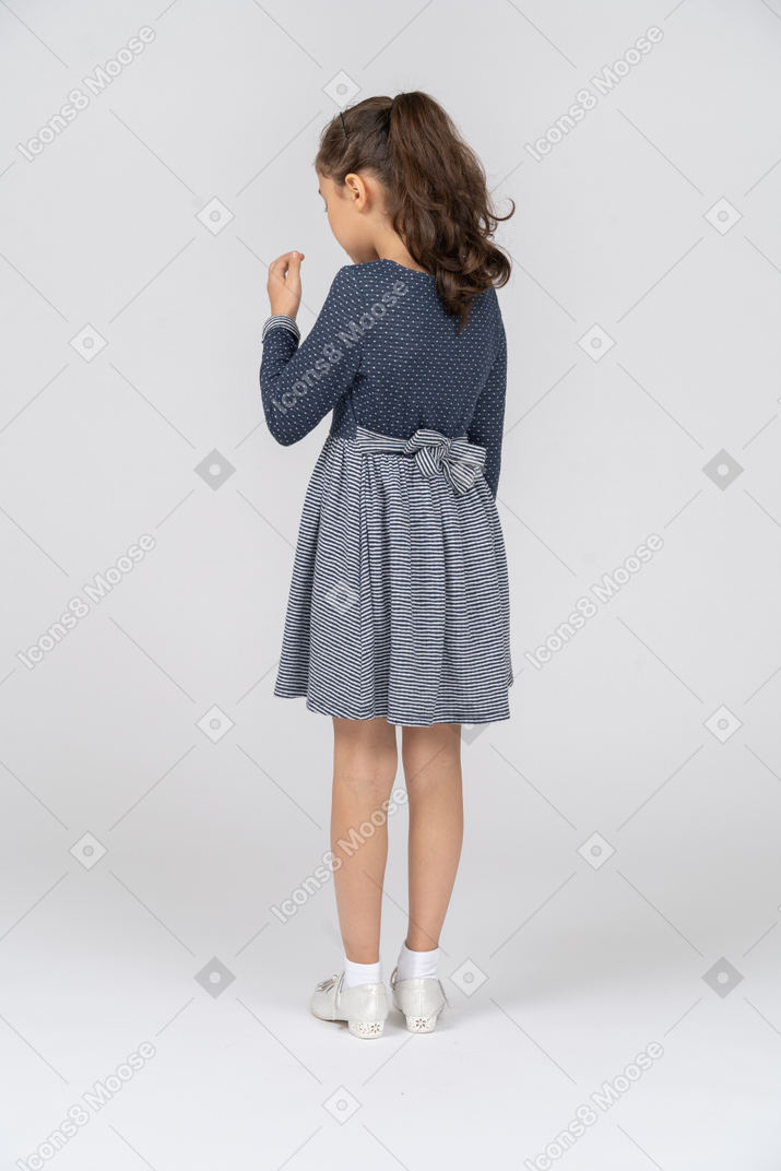Vista traseira de três quartos de uma garota levantando a mão