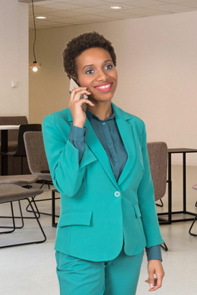 A woman in a turquoise suit talking on a cell phone