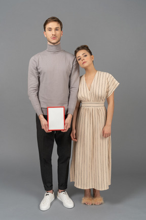 Vista frontal de um jovem casal com uma placa em branco