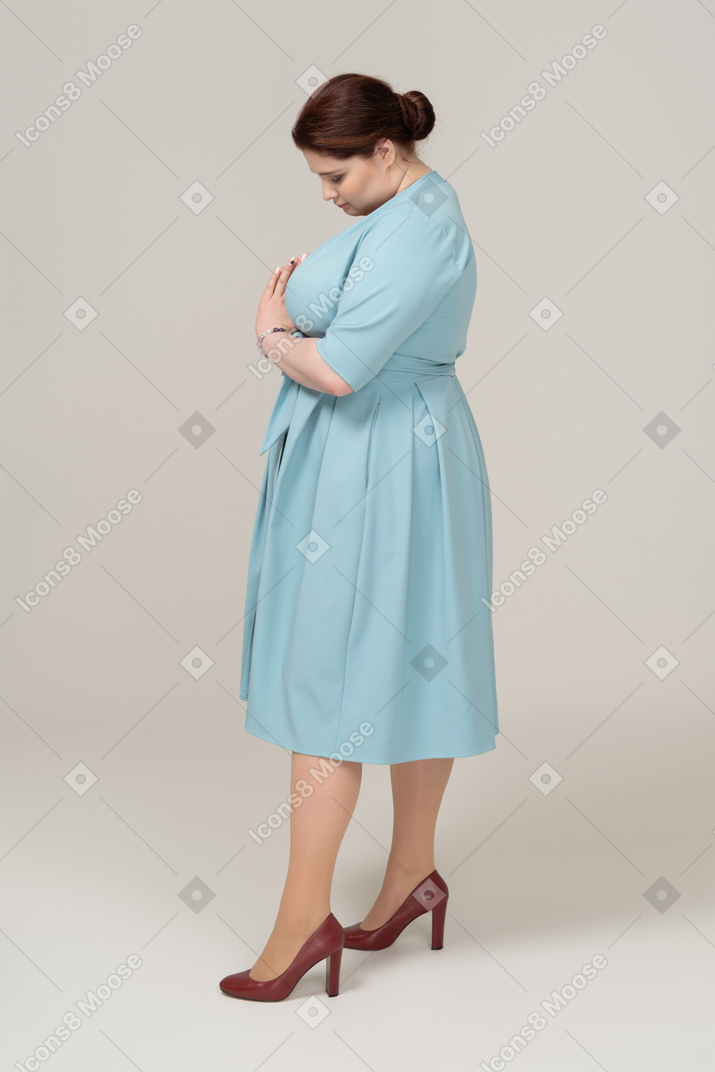 Вид сбоку на женщину в голубом платье, смотрящую вниз