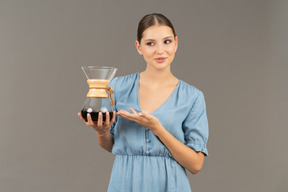 Vista frontal de uma jovem de vestido azul segurando uma jarra de vinho