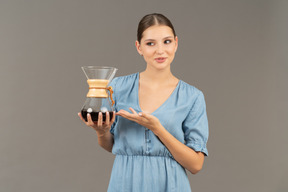 Front view of a young woman in blue dress holding a pitcher of wine