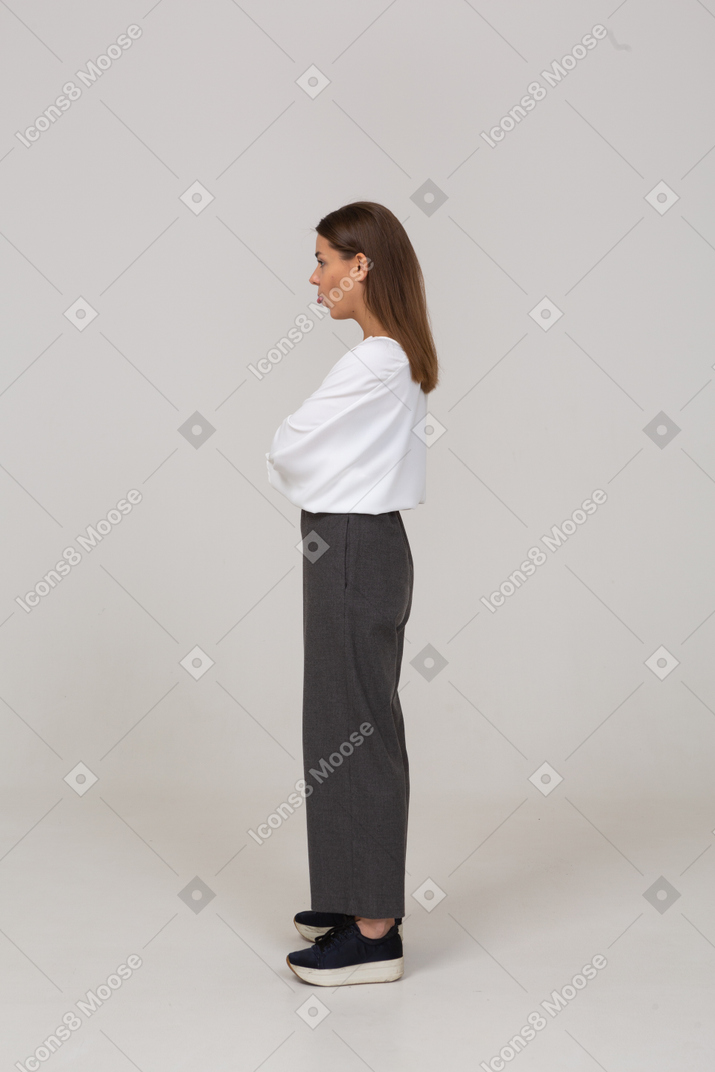 Side view of a young lady in office clothing crossing arms and showing tongue