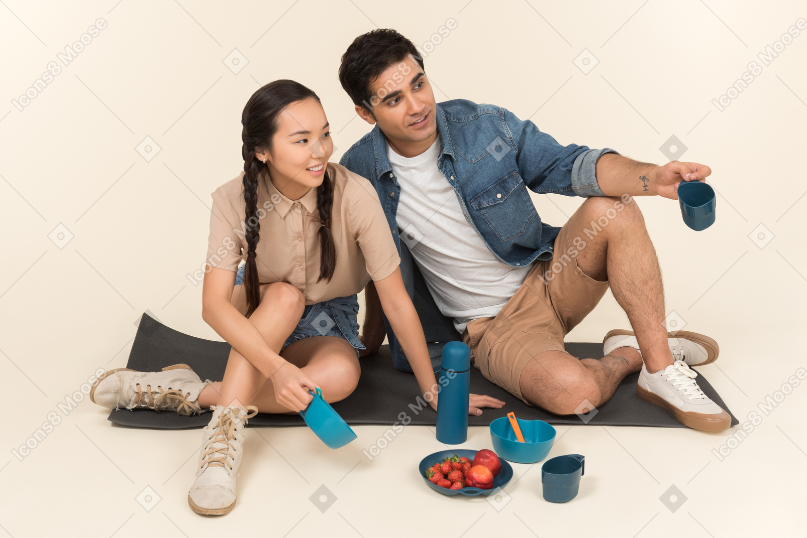 Jovem casal interracial sentado no karimat e apontando
