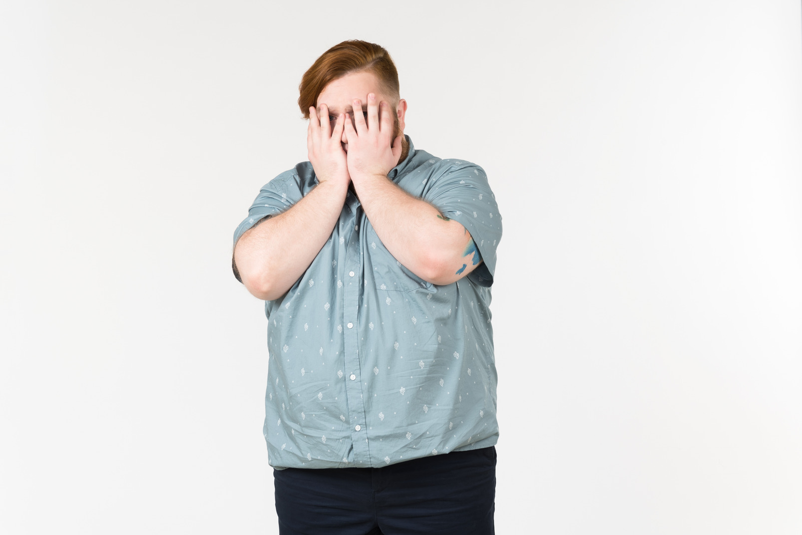 Sad young overweight man closing his face with hands