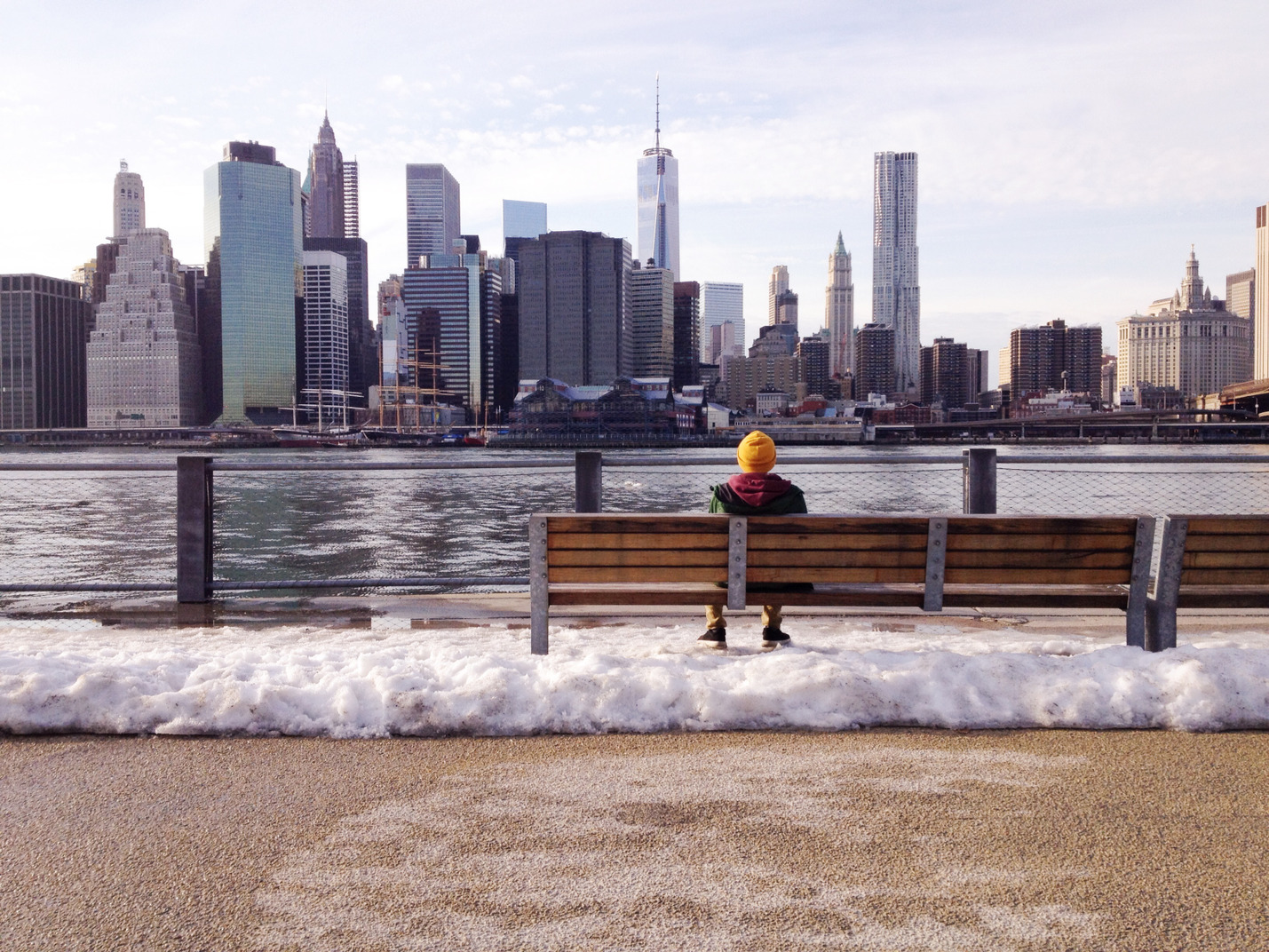 Homem sentado em um banco e apreciando a vista da cidade