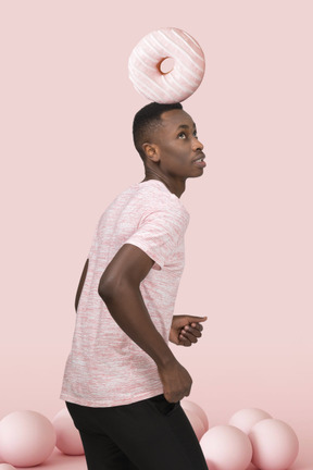 Young man standing with a big donut on his head