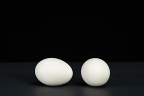 黒の背景に別々に横たわっている2つの卵