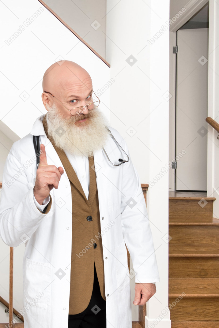 Um velho médico apontando o dedo para cima