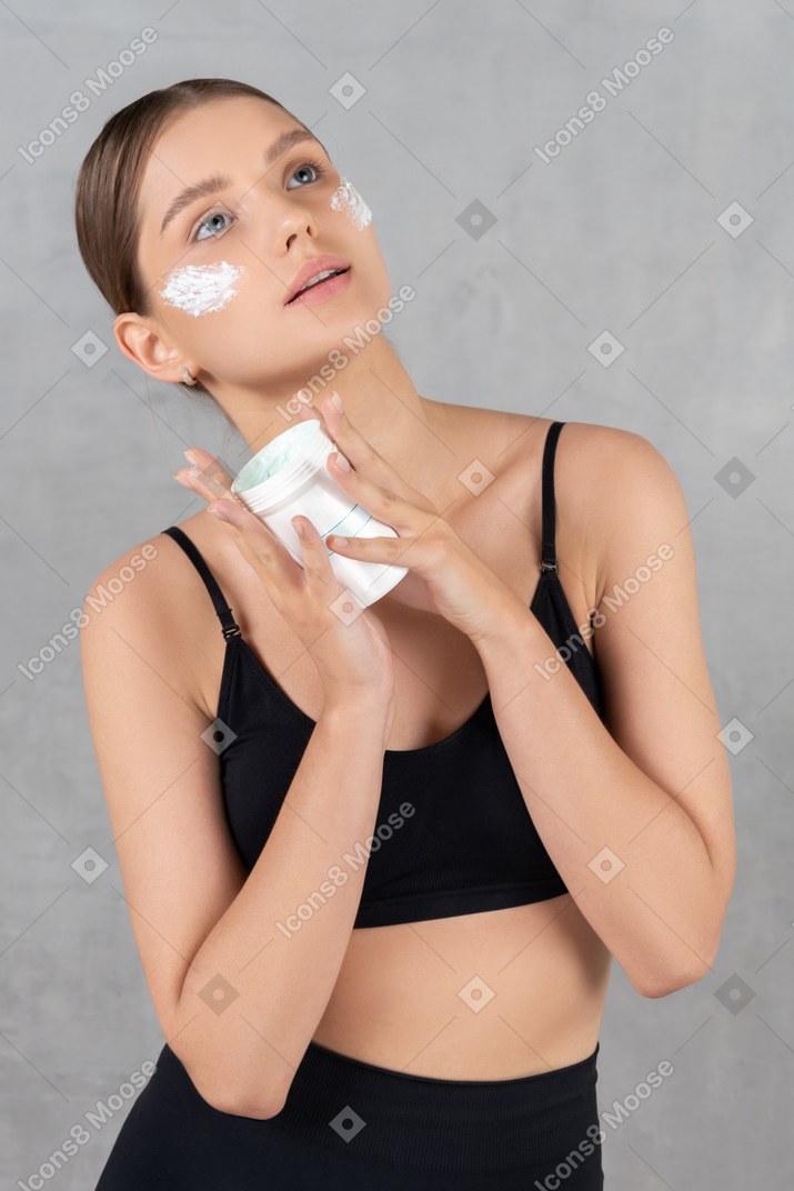 Young beautiful woman holding jar of face cream
