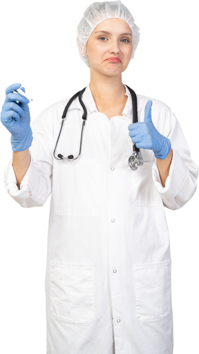 Vue de face d'une jeune femme médecin avec stéthoscope tenant un thermomètre et montrant le pouce vers le haut