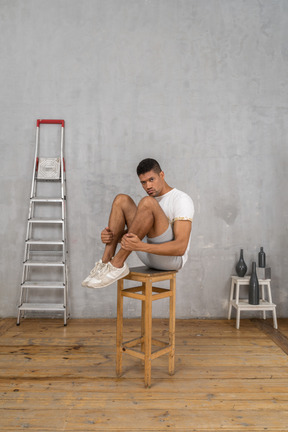 Homme assis sur une chaise avec ses genoux pliés