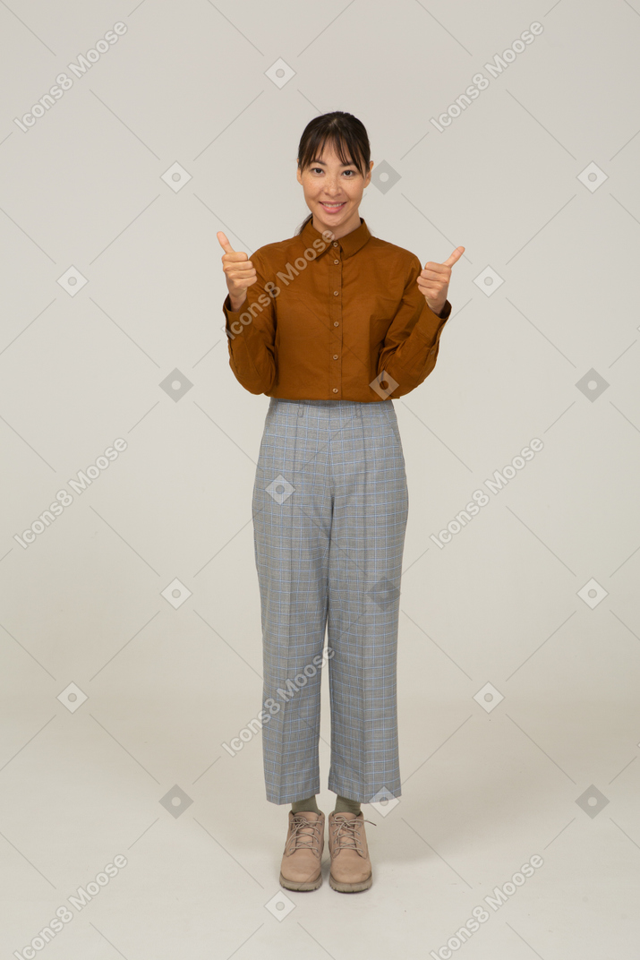Front view of a young asian female in breeches and blouse showing thumbs up