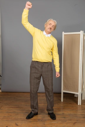 Front view of an old serious man raising his hand