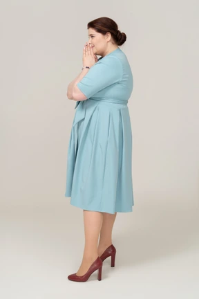 Woman in blue dress standing in profile